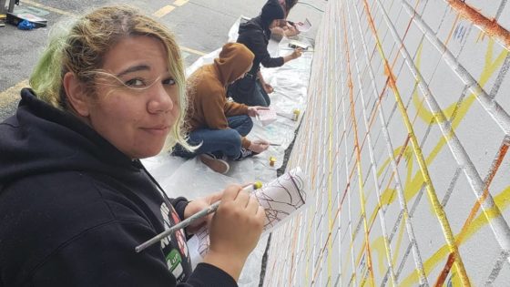 artists painting mural on wall